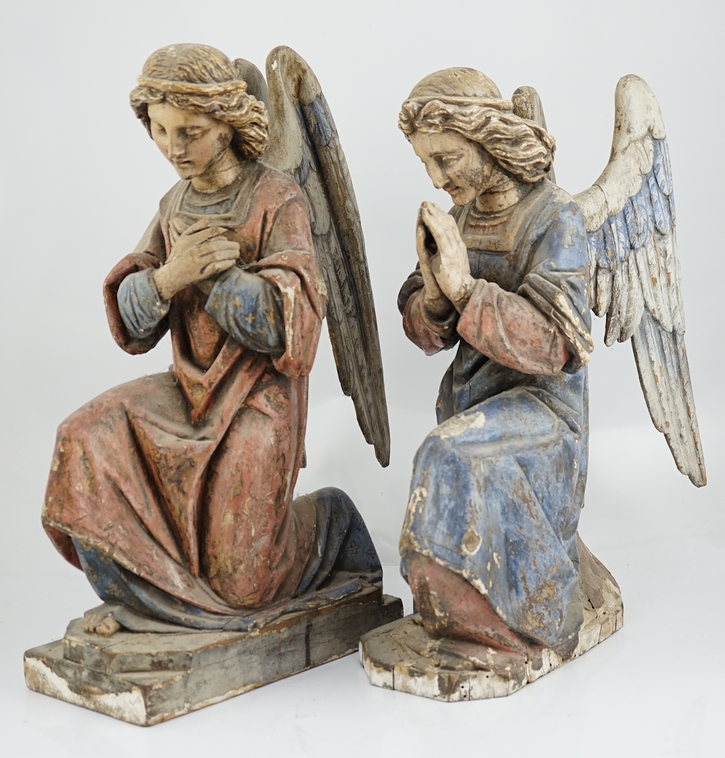 A pair of late 19th century polychrome carved painted pine praying archangels